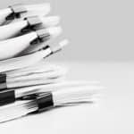 Stack of report paper documents for business desk. Business offices concept, soft focus.