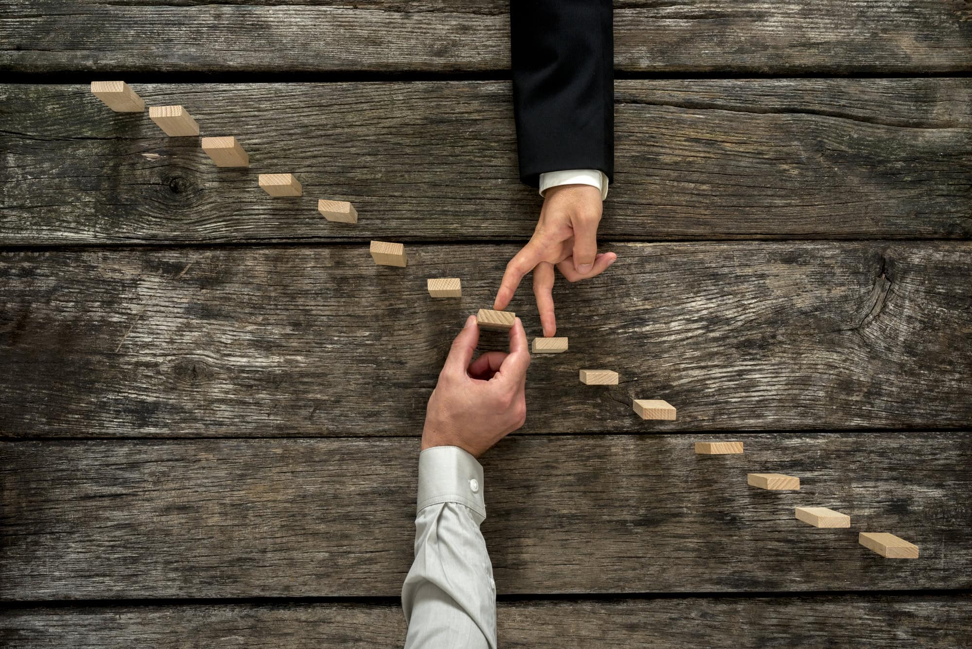 Conceptual image of business partnership and support Strategic decision-making and business growth represented with wooden dominoes being aligned.